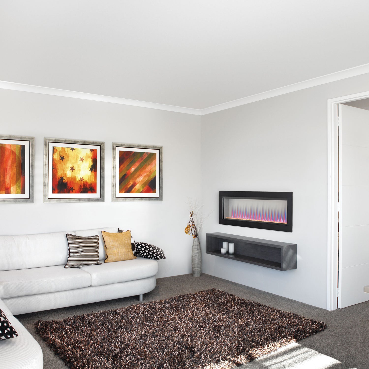 Modern living room with a white sofa, decorative pillows, and a wall-mounted electric fireplace.