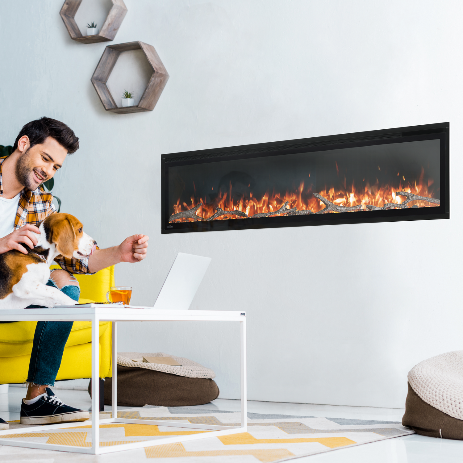 Man sitting on a yellow couch with a dog, next to a modern electric fireplace in a living room.