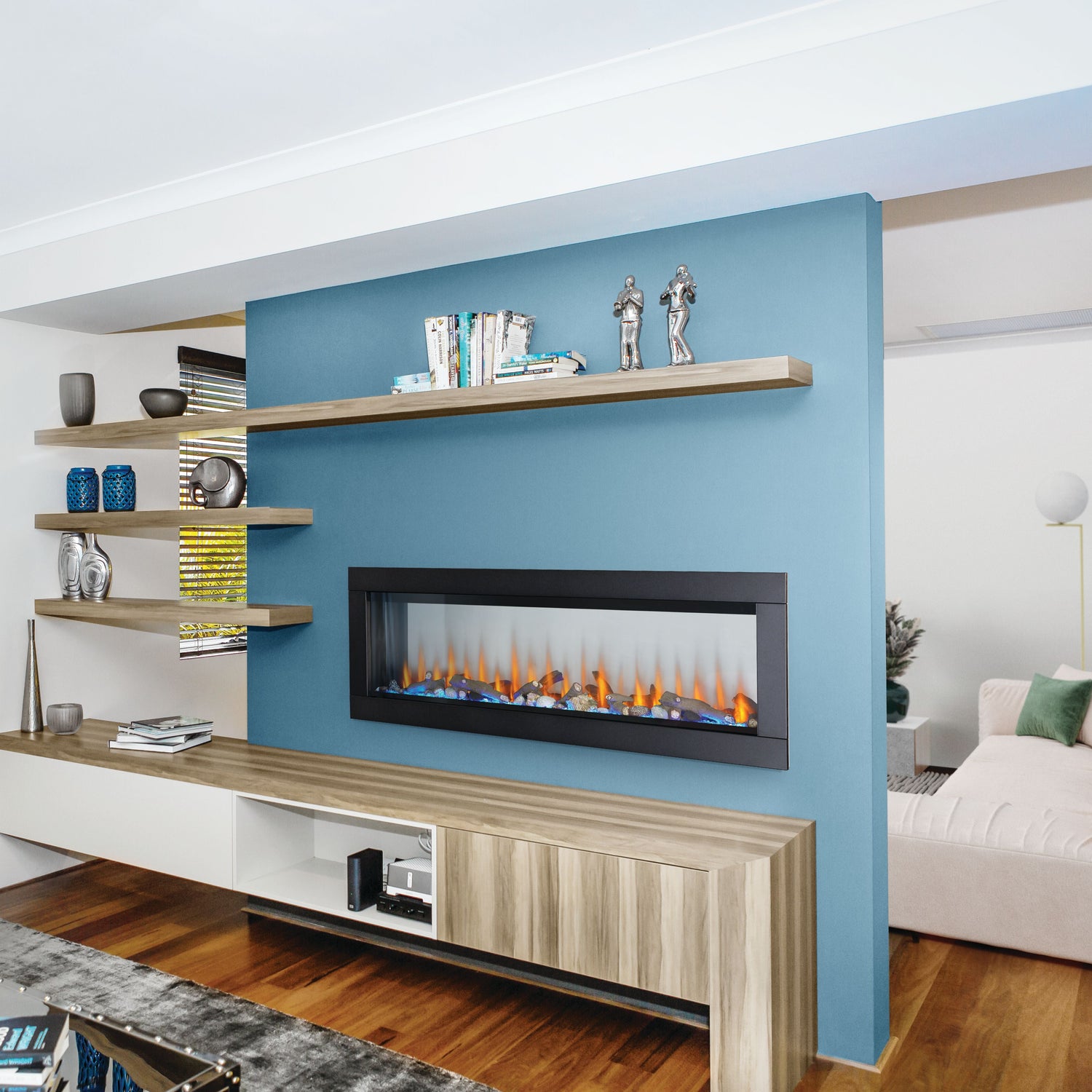 Modern living room with a blue wall, electric fireplace, and shelves.